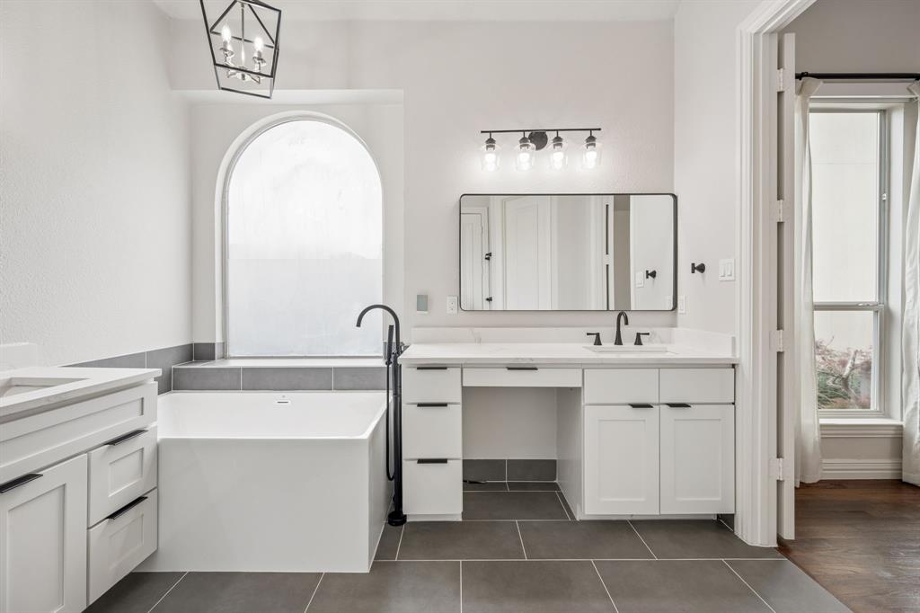 3309 Ricci Lane Irving, TX 75062 - Photo 19 of 36 Bathroom with two vanities, a freestanding bath, dark tile patterned floors, and suspended lighting