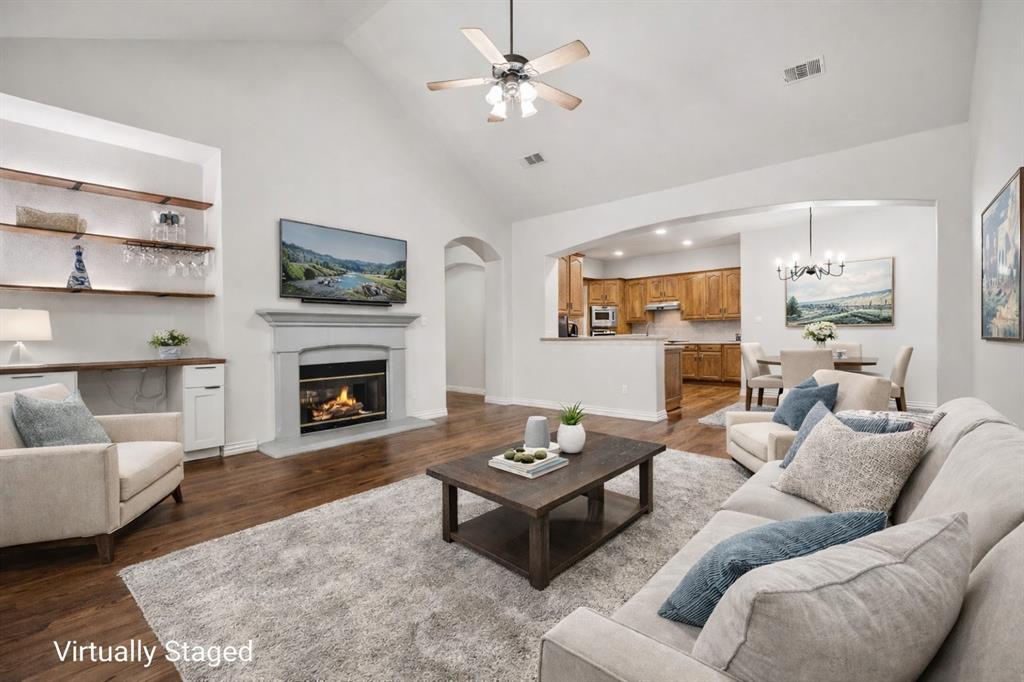 3309 Ricci Lane Irving, TX 75062 - Photo 2 of 36 Living room featuring a glass covered fireplace, hardwood floors, ceiling fan, lofted ceiling, and arched walkways