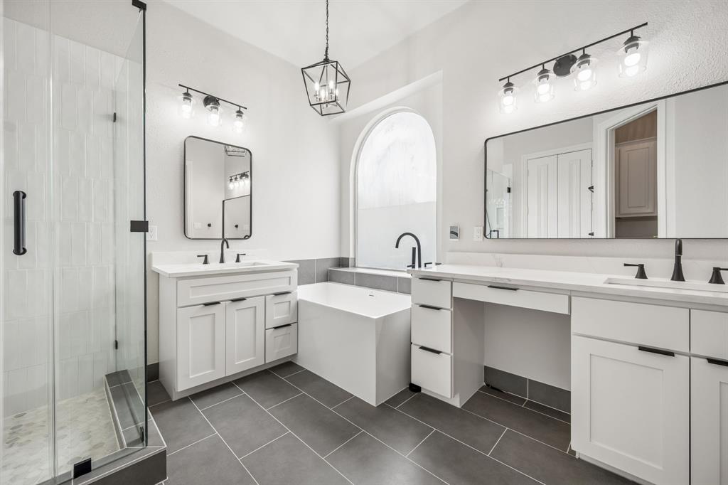 3309 Ricci Lane Irving, TX 75062 - Photo 20 of 36 Full bath featuring a shower stall, a freestanding bath, two vanities, and dark tile patterned flooring