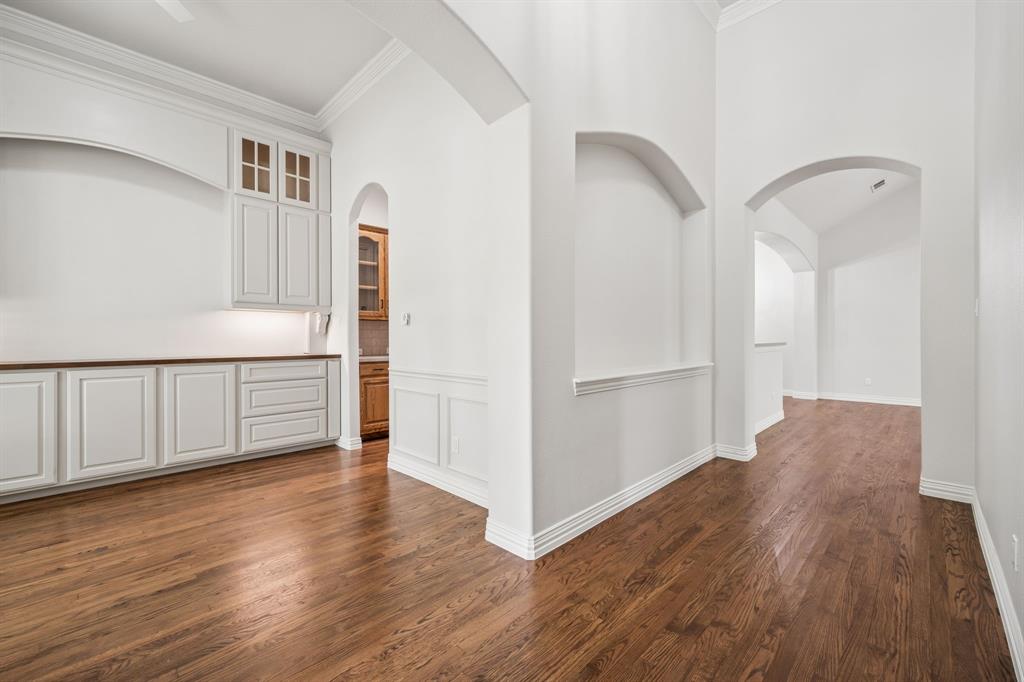 3309 Ricci Lane Irving, TX 75062 - Photo 6 of 36 Corridor featuring crown molding, hardwood floors, a high ceiling, a wainscoted wall, and a decorative nicche