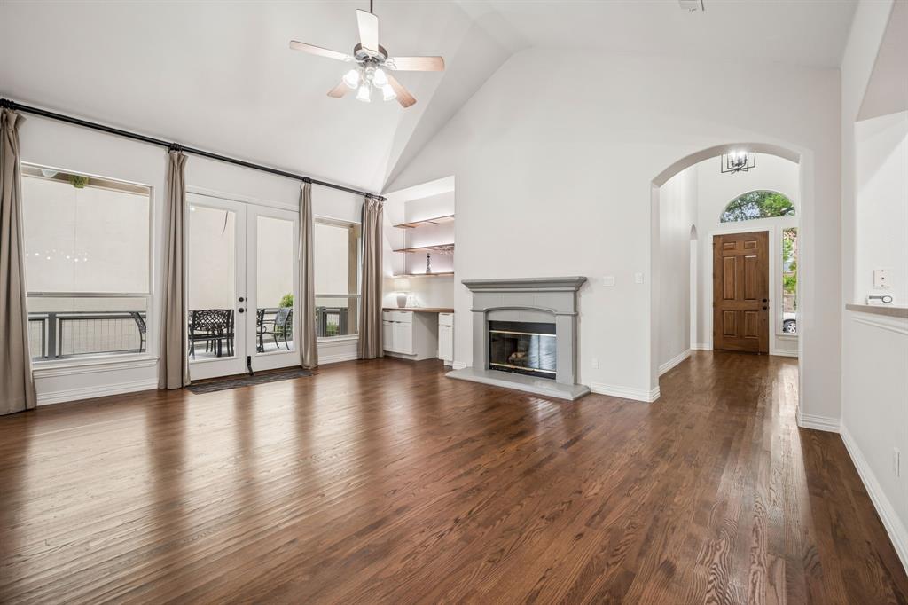 3309 Ricci Lane Irving, TX 75062 - Photo 8 of 36 Unfurnished living room with ceiling fan, hard wood flooring, vaulted ceiling, arched walkways, and a glass covered fireplace