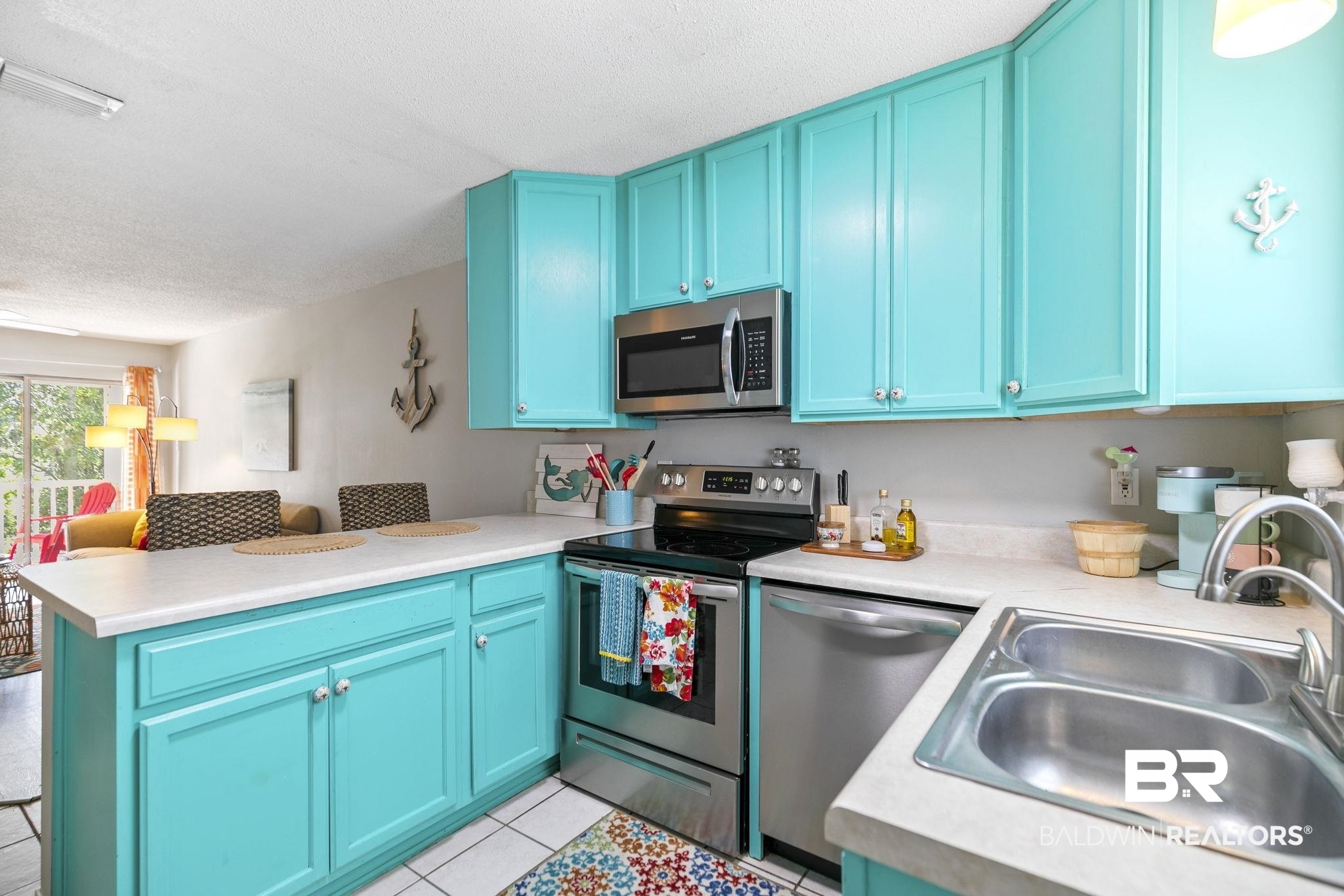 25957 Canal Road, Unit 302 Orange Beach, AL 36561 - Photo 7 of 26 Kitchen with appliances with stainless steel finishes, sink, a textured ceiling, light tile patterned floors, and kitchen peninsula