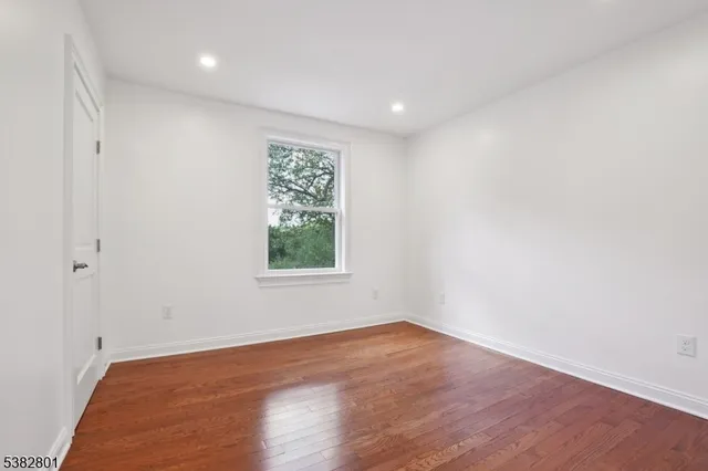 an empty room with wooden floor and window