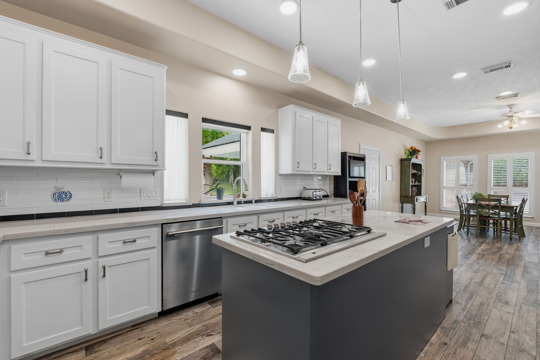 11714 Creek View Lane Conroe, TX 77385 - Photo 15 of 46 a kitchen with a stove a sink a kitchen island with chairs and wooden floor