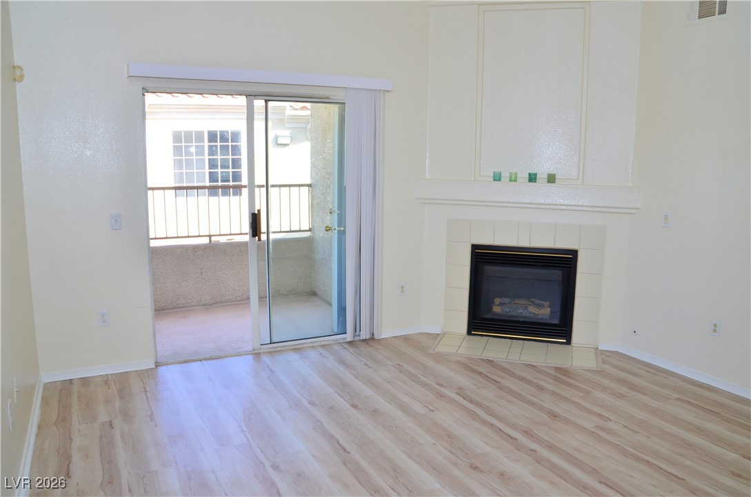 1881 West Alexander Road, Unit 2101 North Las Vegas, NV 89032 - Photo 11 of 37 Unfurnished living room with light wood-style floors and a tiled fireplace