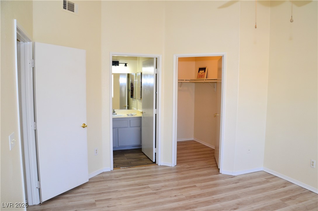 1881 West Alexander Road, Unit 2101 North Las Vegas, NV 89032 - Photo 14 of 37 Unfurnished bedroom with light wood finished floors, a spacious closet, connected bathroom, and a ceiling fan