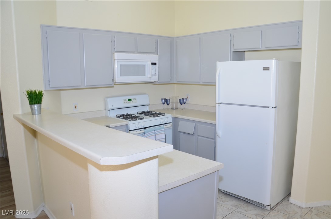 1881 West Alexander Road, Unit 2101 North Las Vegas, NV 89032 - Photo 3 of 37 Kitchen featuring white appliances, light countertops, gray cabinets, and a peninsula