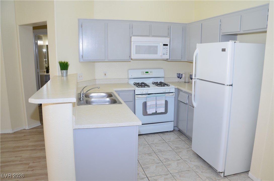 1881 West Alexander Road, Unit 2101 North Las Vegas, NV 89032 - Photo 4 of 37 Kitchen featuring white appliances, a peninsula, light countertops, and gray cabinets