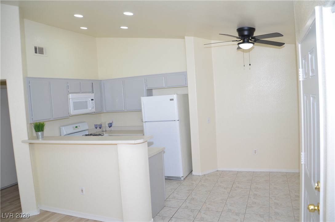1881 West Alexander Road, Unit 2101 North Las Vegas, NV 89032 - Photo 6 of 37 Kitchen featuring white appliances, gray cabinets, light countertops, a high ceiling, and a peninsula