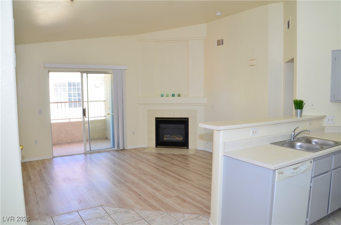 1881 West Alexander Road, Unit 2101 North Las Vegas, NV 89032 - Photo 8 of 37 Kitchen featuring vaulted ceiling, white dishwasher, light countertops, a peninsula, and a tile fireplace