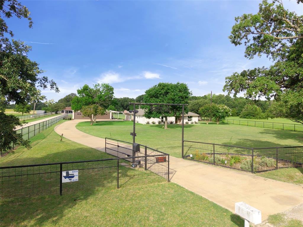 380 Farr Altom Road Seagoville, TX 75159 - Photo 22 of 30 Gated entry with a concrete drive, expansive green lawn, mature trees, and a perimeter fence