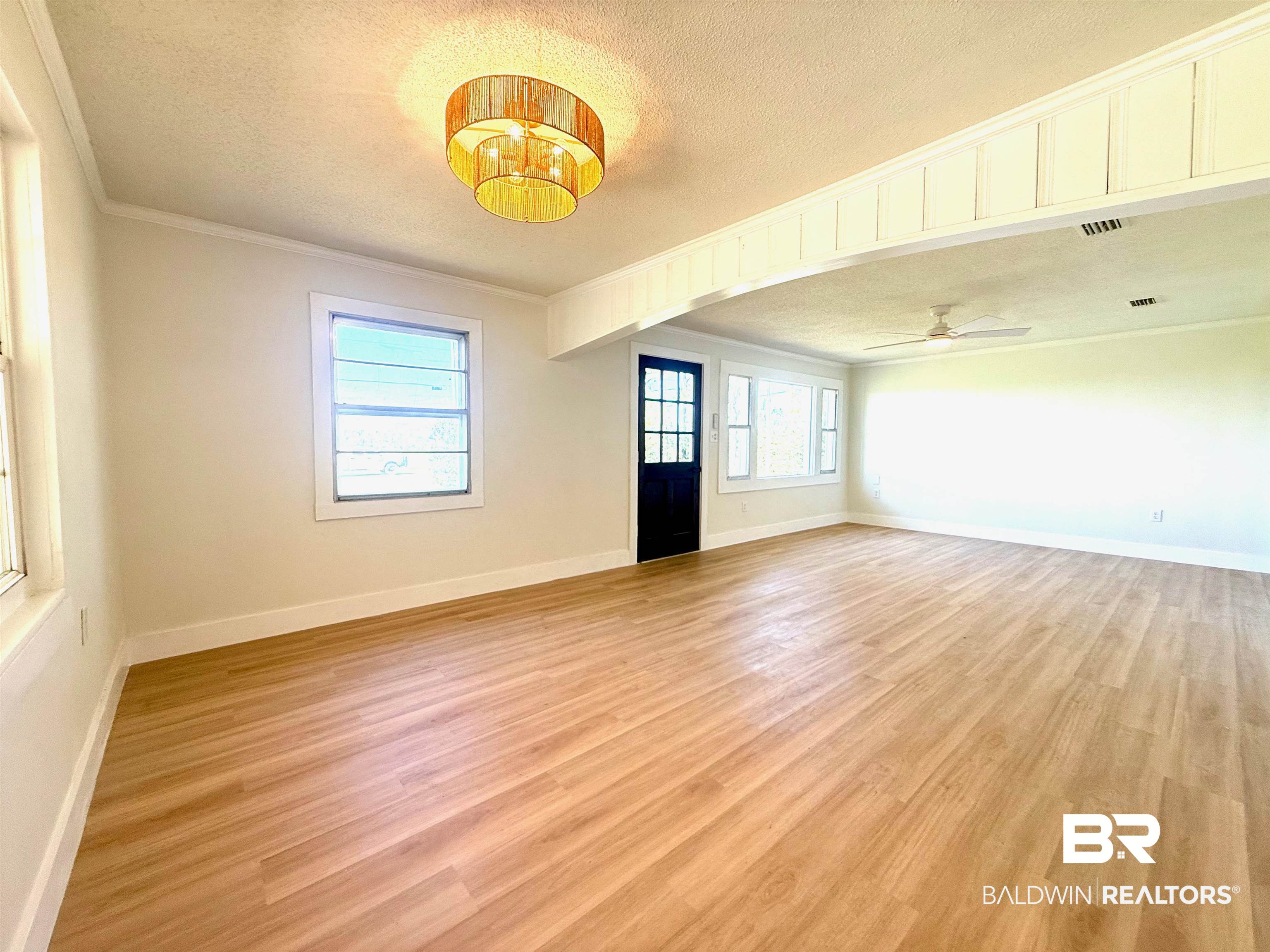 11698 Poser Road Foley, AL 36535 - Photo 6 of 20 Empty room with a textured ceiling, ornamental molding, light wood-type flooring, and a chandelier