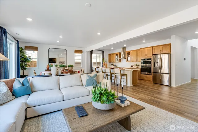 a living room with furniture kitchen and a wooden floor