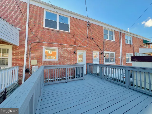 a view of a brick house with wooden deck