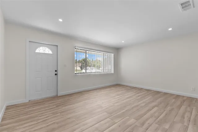 a view of an empty room with wooden floor and a window