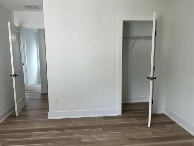 a view of a hallway with wooden floor and closet area
