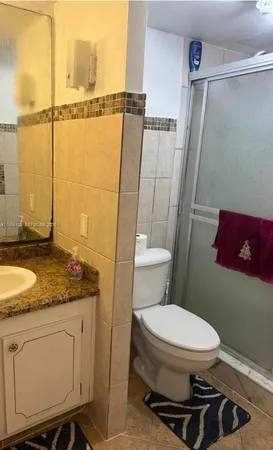 a bathroom with a granite countertop sink toilet and shower