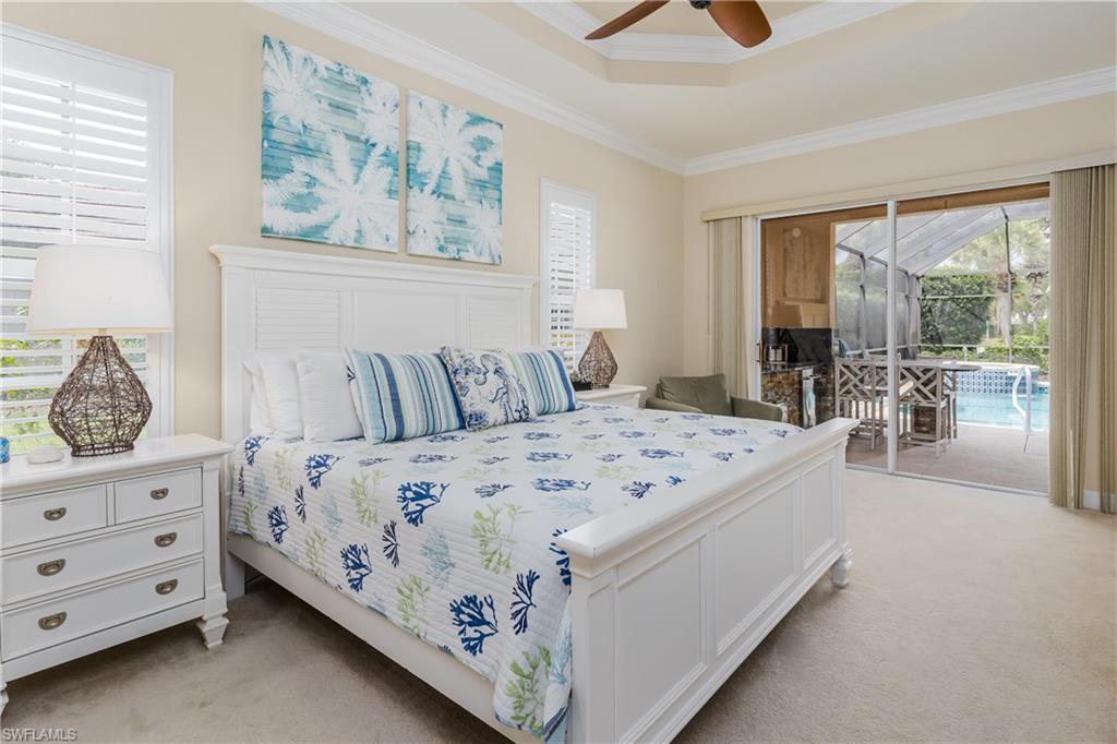 8754 Hideaway Harbor Court Naples, FL 34120 - Photo 22 of 49 a bedroom with a large bed and a chandelier