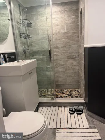 a bathroom with a sink a toilet a mirror and shower