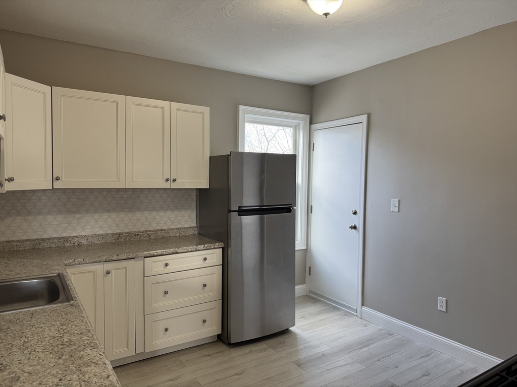 630 Metropolitan Avenue, Unit 3 Boston, MA 02136 - Photo 4 of 31 a kitchen with cabinets appliances and wooden floor