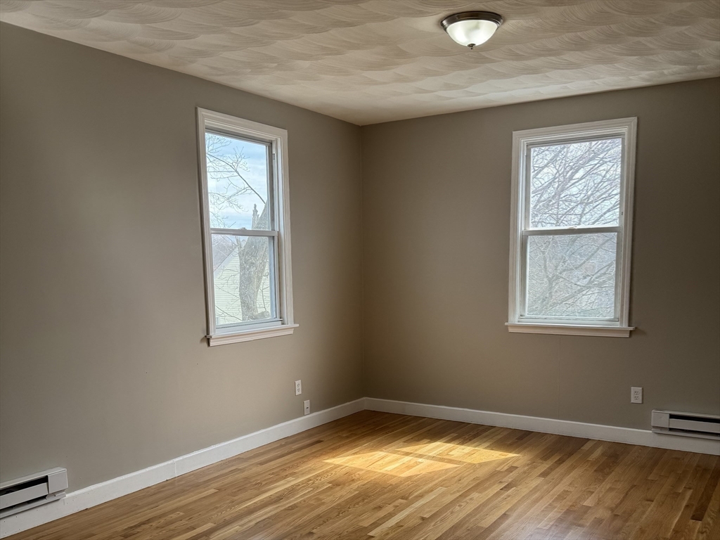 630 Metropolitan Avenue, Unit 3 Boston, MA 02136 - Photo 7 of 31 a view of an empty room with wooden floor and a window