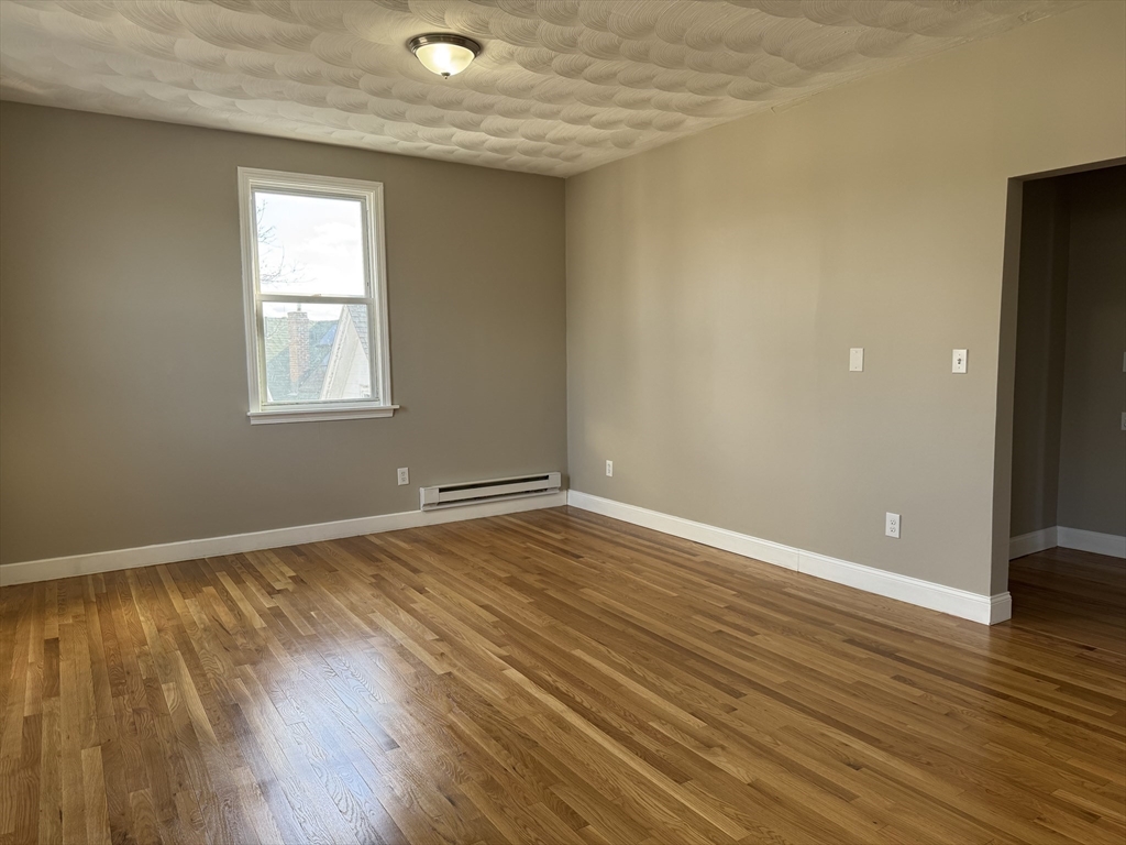 630 Metropolitan Avenue, Unit 3 Boston, MA 02136 - Photo 8 of 31 an empty room with wooden floor and windows