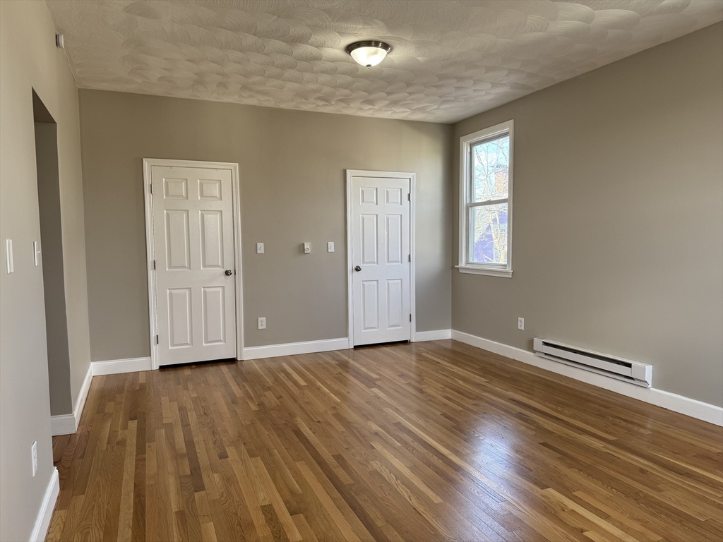 630 Metropolitan Avenue, Unit 3 Boston, MA 02136 - Photo 9 of 31 an empty room with wooden floor and windows