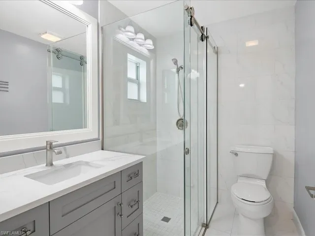 a bathroom with a shower sink vanity mirror and toilet