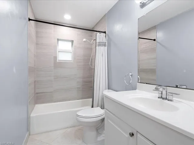 a bathroom with a bathtub shower sink vanity mirror and toilet