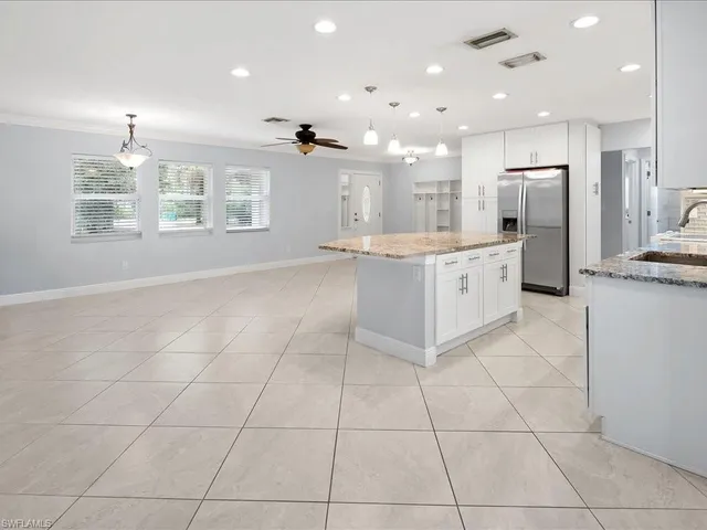 a large kitchen with granite countertop a large counter top and stainless steel appliances