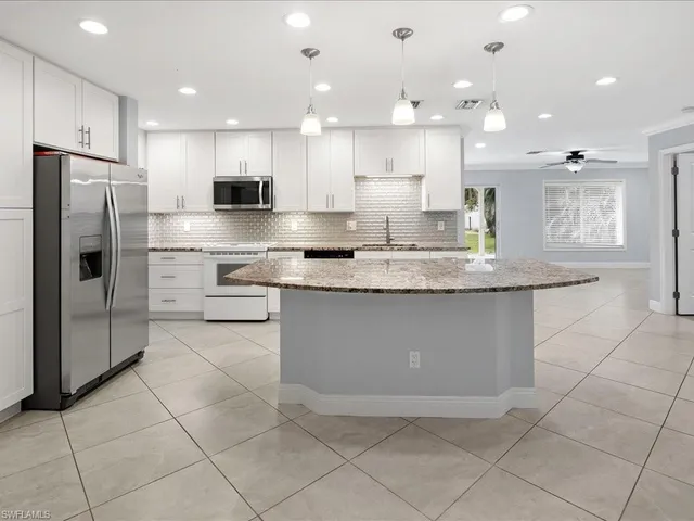 a large kitchen with stainless steel appliances granite countertop a stove a sink a microwave and a refrigerator