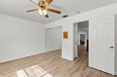 a view of a room with wooden floor and a ceiling fan