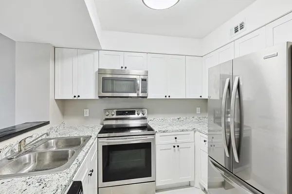 a kitchen with white cabinets sink and stainless steel appliances
