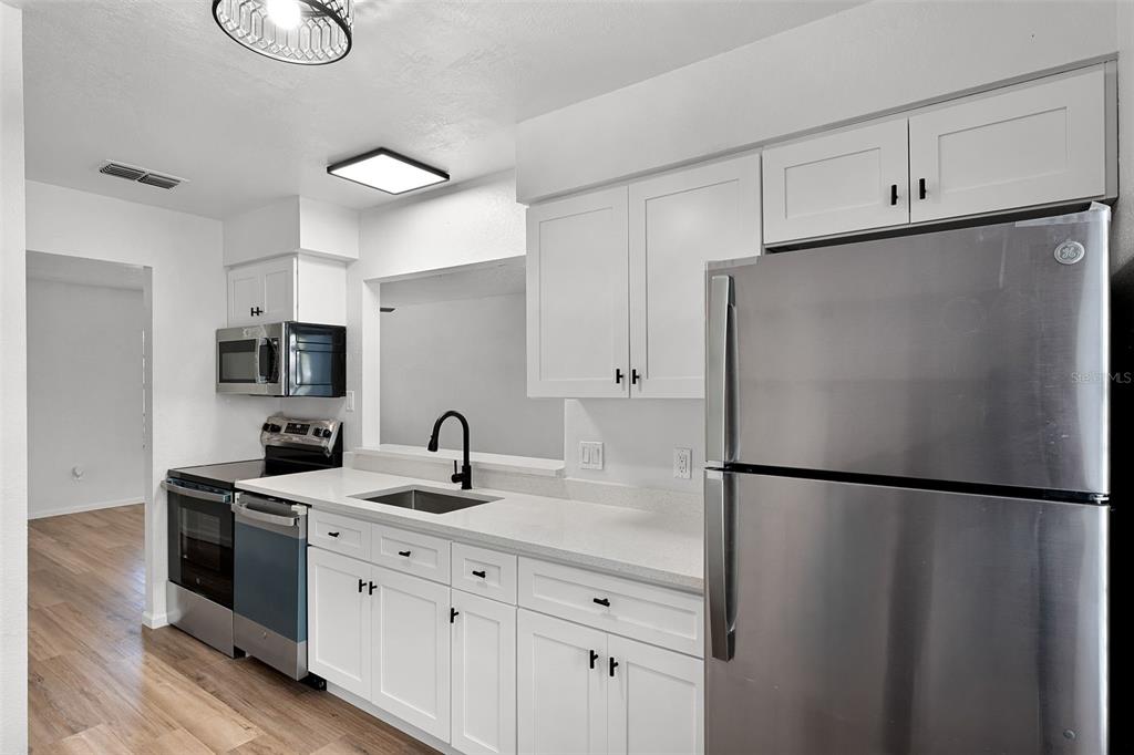 2722 Graduate Court Orlando, FL 32826 - Photo 11 of 33 a kitchen with stainless steel appliances granite countertop a refrigerator a sink and a stove