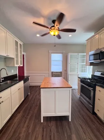 a kitchen with a stove a sink a refrigerator cabinets and wooden floor