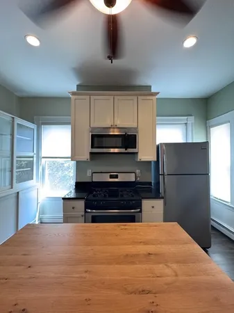 a kitchen with stainless steel appliances granite countertop a stove a refrigerator and a sink with wooden floor