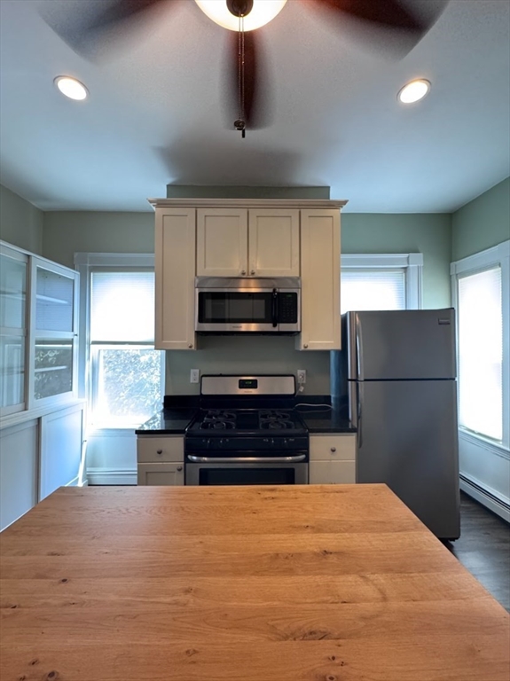 401 Washington Street, Unit 3 Cambridge, MA 02139 - Photo 4 of 13 a kitchen with stainless steel appliances granite countertop a stove a refrigerator and a sink with wooden floor
