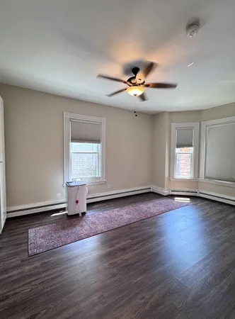 a view of an empty room with a window and wooden floor