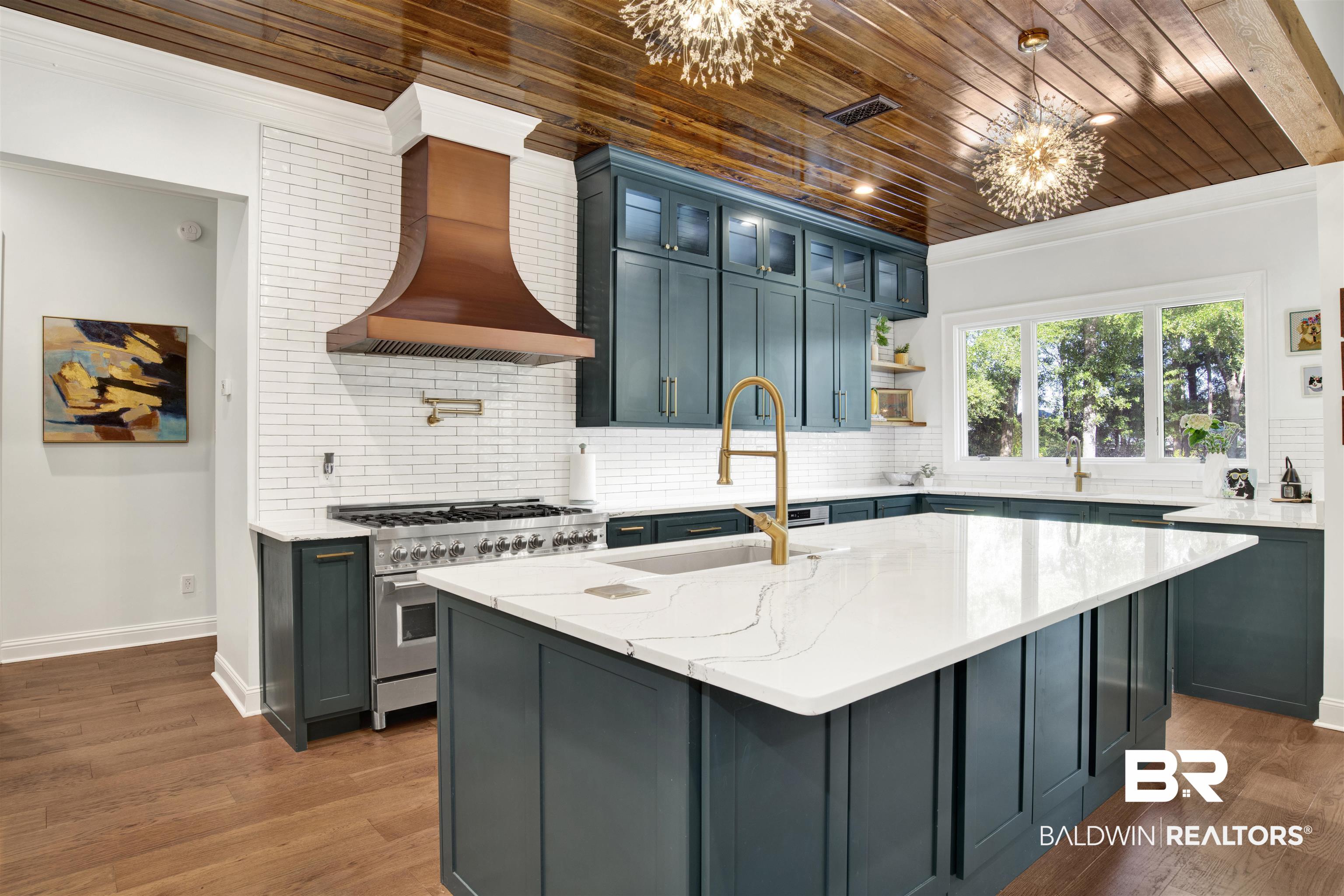11116 Redfern Road Daphne, AL 36526 - Photo 26 of 46 Kitchen featuring glass insert cabinets, tasteful backsplash, light stone countertops, high end range, and a kitchen island with sink