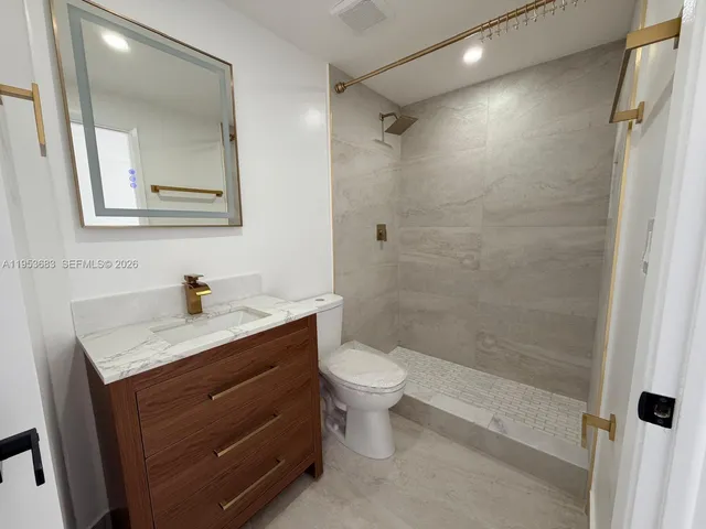 a bathroom with a granite countertop sink toilet and shower