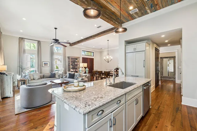 a living room with furniture a rug kitchen view and a chandelier