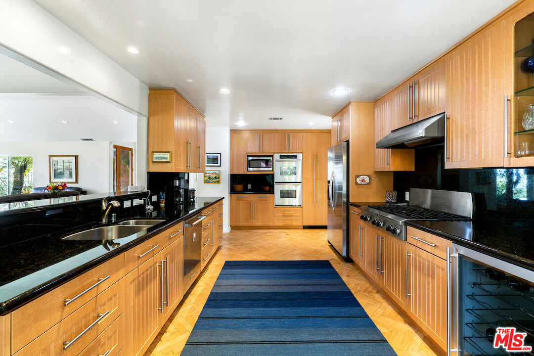 1336 Las Canoas Road Pacific Palisades, CA 90272 - Photo 14 of 37 a large kitchen with stainless steel appliances kitchen island granite countertop a large counter top and a stove top oven
