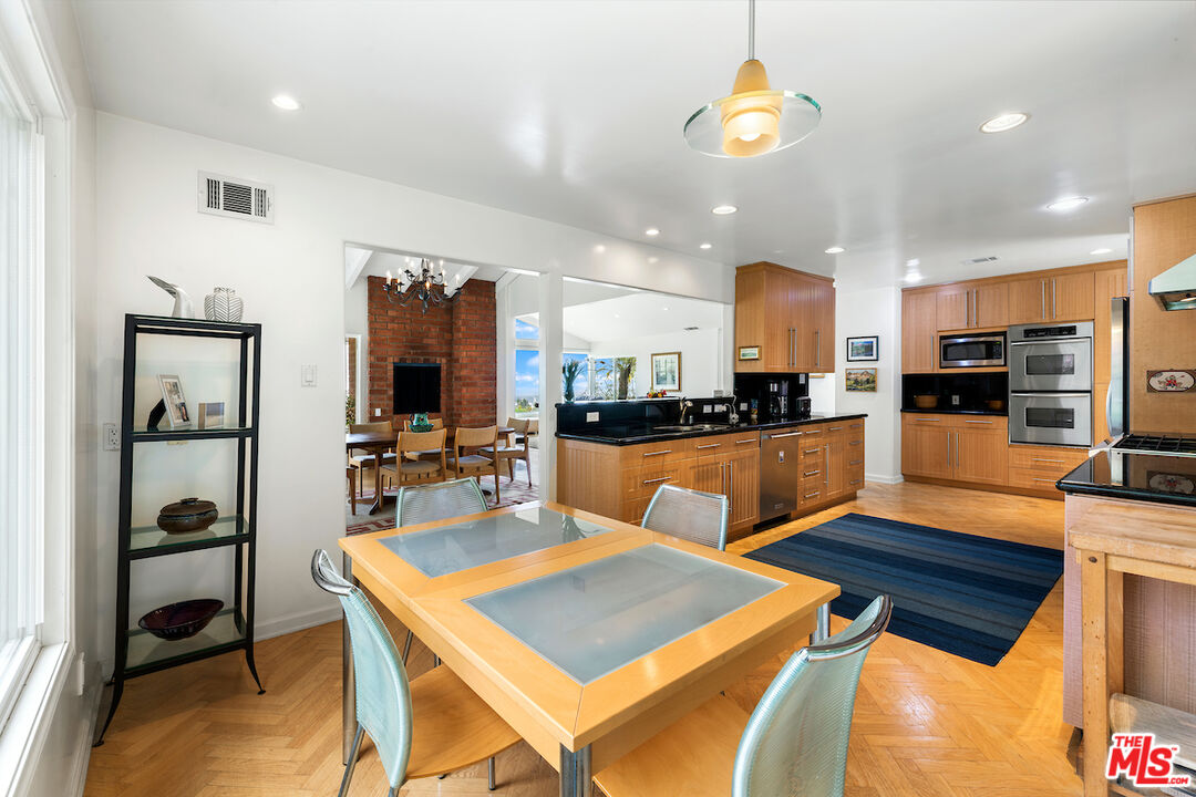 1336 Las Canoas Road Pacific Palisades, CA 90272 - Photo 17 of 37 a kitchen with stainless steel appliances kitchen island granite countertop a refrigerator a stove a microwave oven a sink with a dining table and chairs