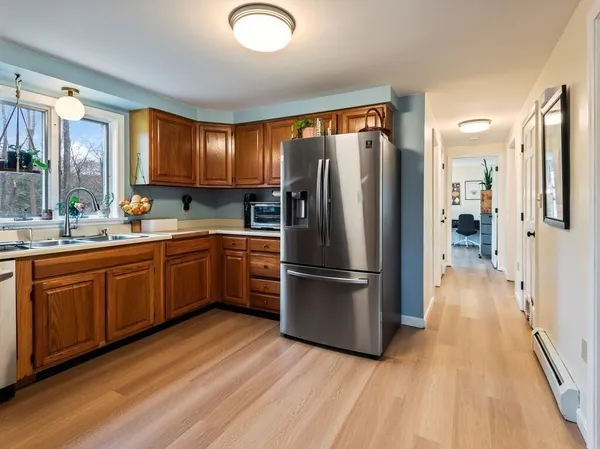 a kitchen with stainless steel appliances granite countertop a sink a stove a refrigerator cabinets and a window