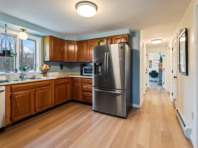 a kitchen with stainless steel appliances granite countertop a sink a stove a refrigerator cabinets and a window