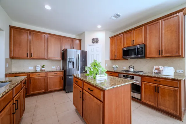 a kitchen with stainless steel appliances granite countertop wooden cabinets a stove top oven a granite counter top and a refrigerator