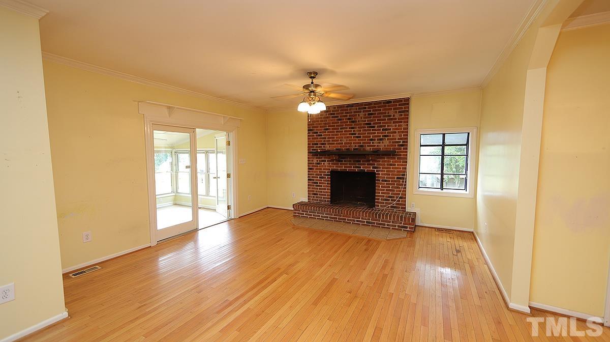 1390 Sanders Road Benson, NC 27504 - Photo 6 of 22 a view of an empty room with wooden floor fireplace and a window