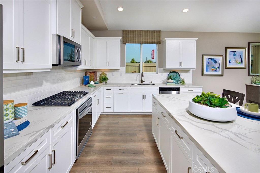 30934 Campania Road Highland, CA 92346 - Photo 7 of 19 a large white kitchen with stainless steel appliances granite countertop a lot of counter space and wooden floor