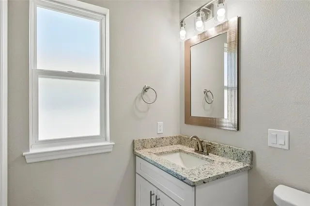 a bathroom with a granite countertop sink and a mirror