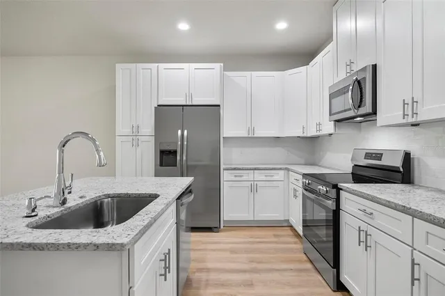 a kitchen with stainless steel appliances granite countertop a stove a sink and a white cabinets